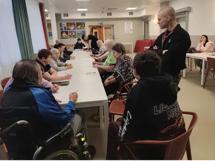 Mieszkańcy i młodzież grają w bingo przy długim stole