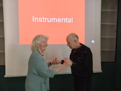 Para mieszkańców tańczy przed ekranem z napisem Instrumental