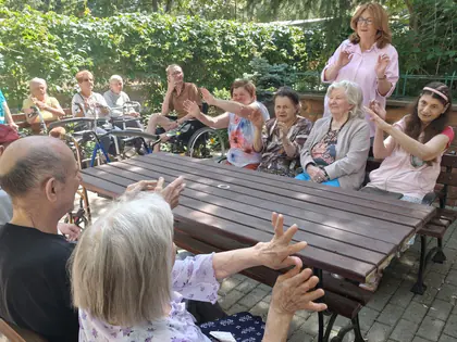 Mieszkańcy machają rękami w rytm piosenki w ogrodzie