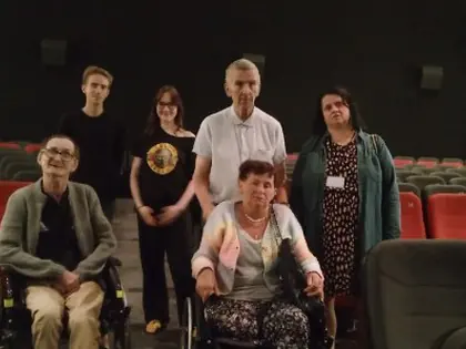 Grupa osób pozuje do zdjęcia, w tle sala kinowa