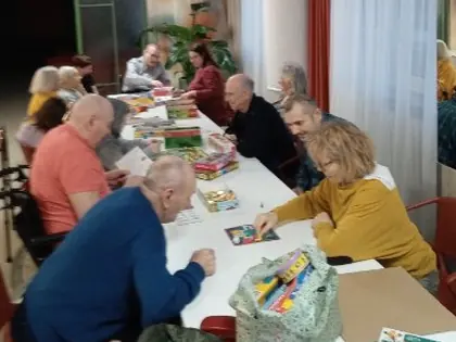 Grupa osób przy długim stole gra w gry planszowe i edukacyjne