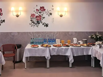 Stoły z poczęstunkiem w sali z malowanymi kwiatami na ścianie