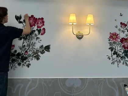 Mężczyzna maluje kwiaty na białej ścianie